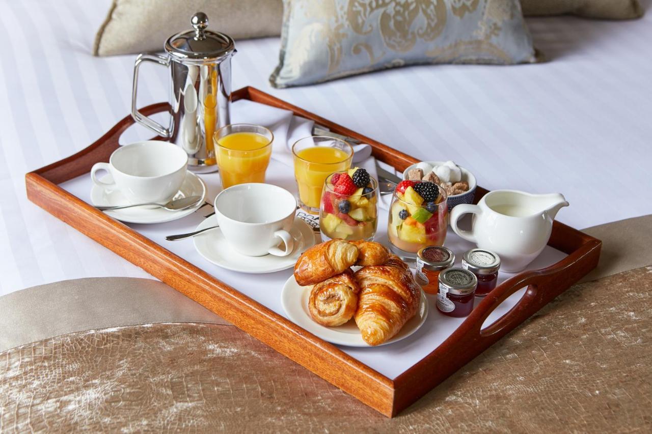 Macdonald Bath Spa Hotel Εξωτερικό φωτογραφία The photo shows a wooden tray arranged with a delightful breakfast spread. On the tray, there are two cups, a coffee pot, and several glasses of orange juice. There's also a small bowl of mixed fruit, featuring various colorful pieces. Additionally, 