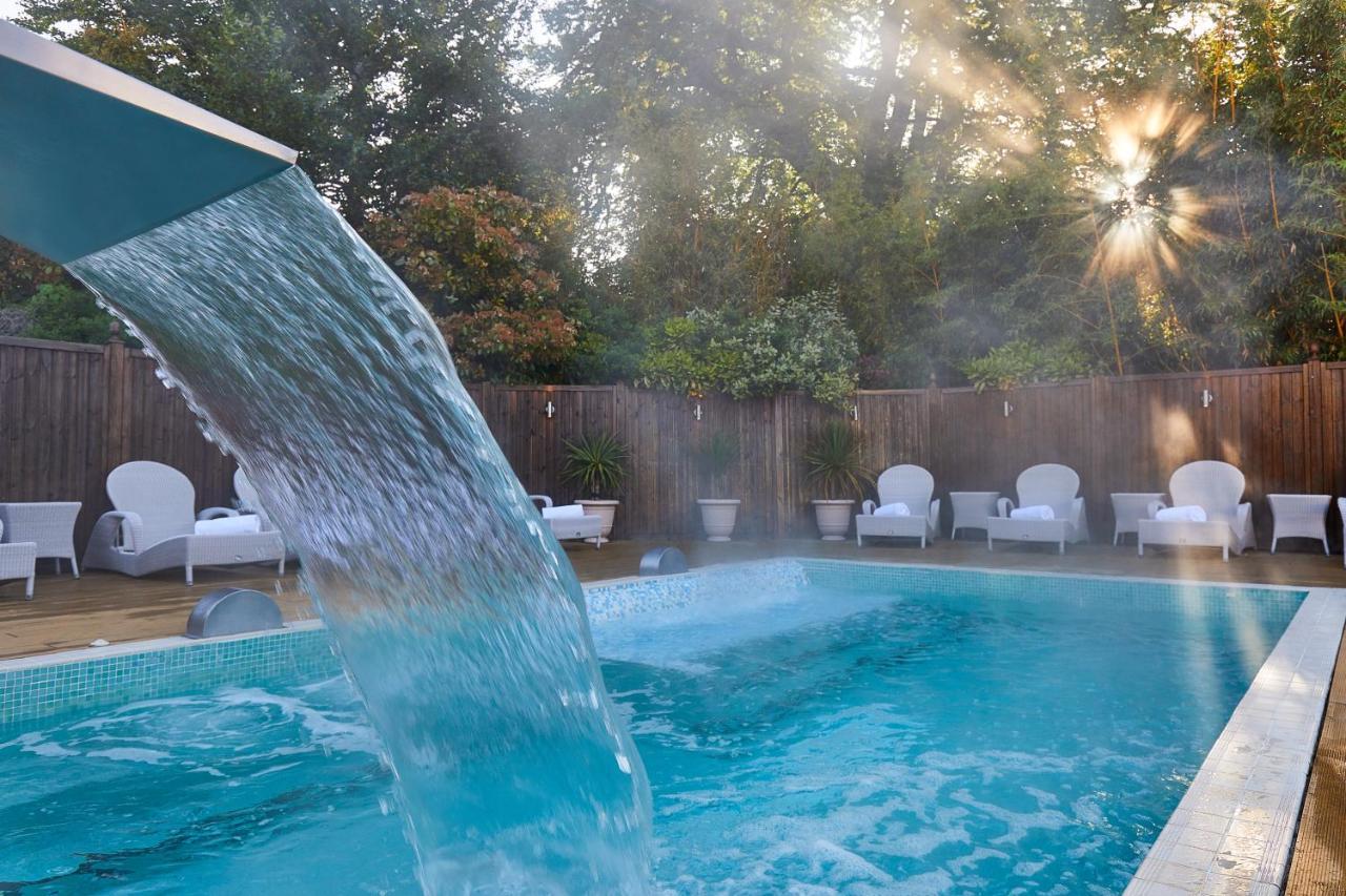 Macdonald Bath Spa Hotel Εξωτερικό φωτογραφία The photo shows a tranquil swimming pool surrounded by greenery. Water is cascading from a feature into the pool, creating a refreshing effect. In the background, there are white lounge chairs positioned neatly along the poolside, inviting relaxation