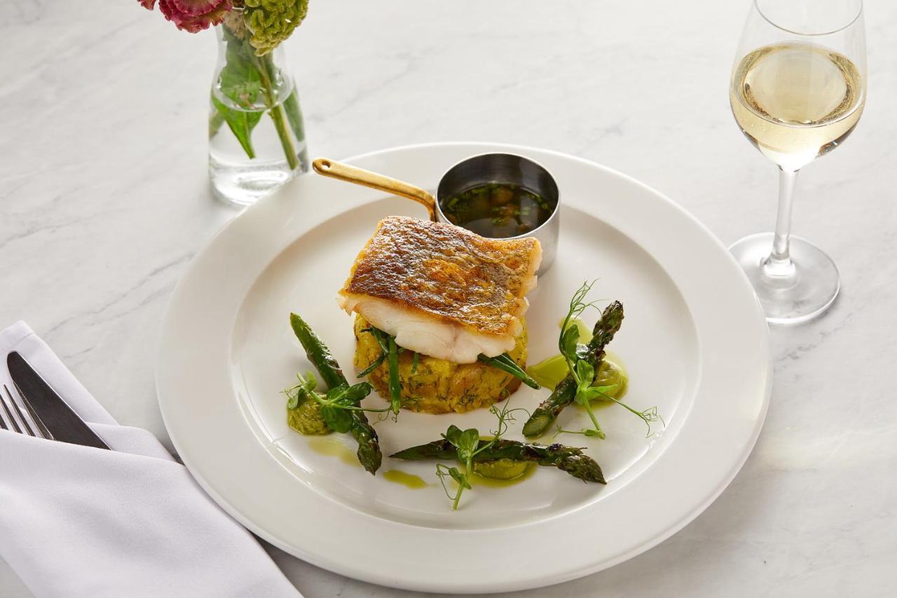 Macdonald Bath Spa Hotel Εξωτερικό φωτογραφία The photo showcases a beautifully plated dish featuring a piece of fish, likely with a crispy skin, resting on a bed of what appears to be a savory cake or puree. Surrounding the fish are fresh asparagus and garnishes, adding a touch of color and fre