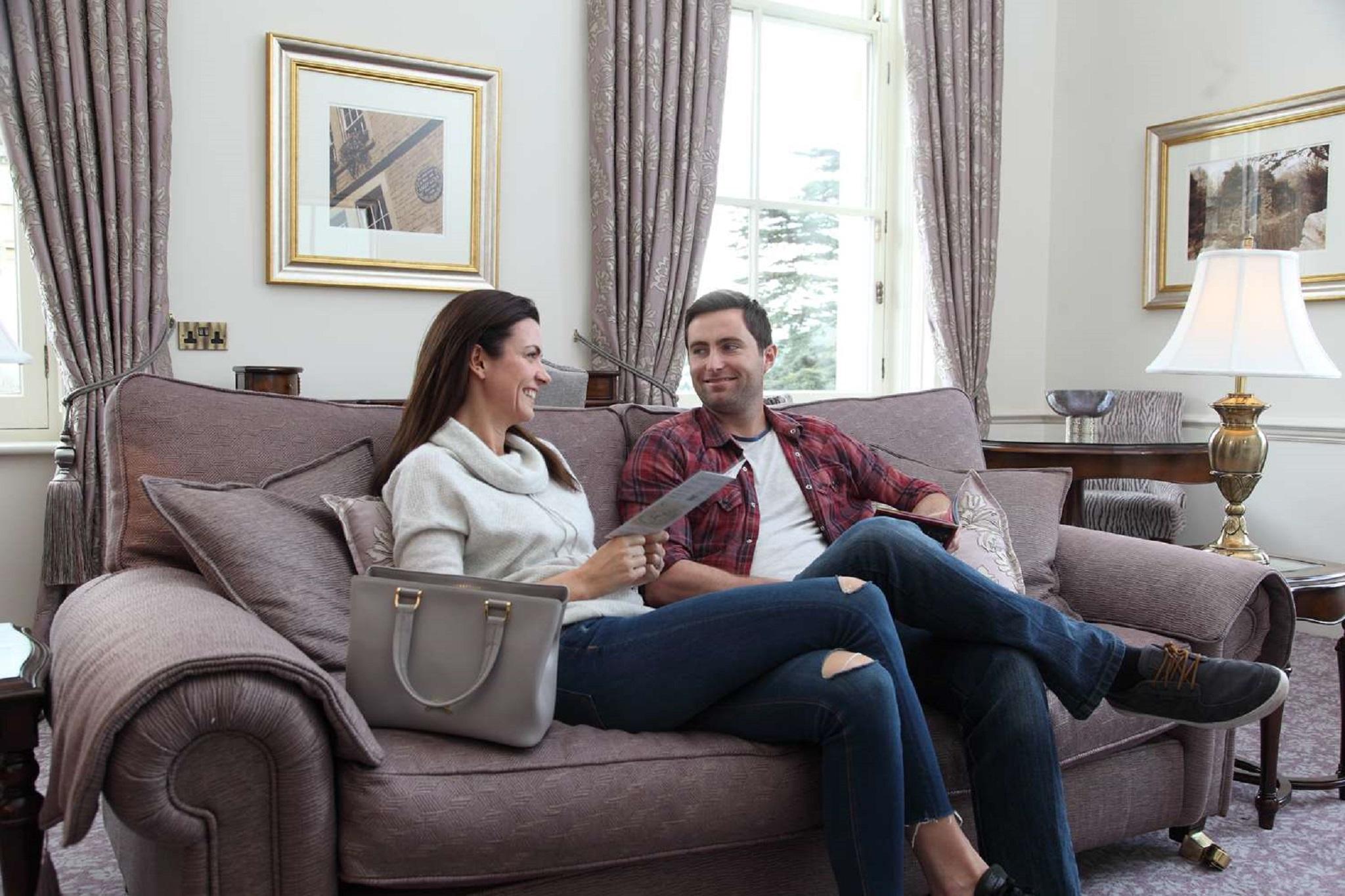 Macdonald Bath Spa Hotel Εξωτερικό φωτογραφία The photo shows a man and a woman sitting together on a comfortable sofa in a well-decorated room. The woman is holding a piece of paper and appears to be engaged in conversation with the man, who is smiling in response. They are both dressed casuall