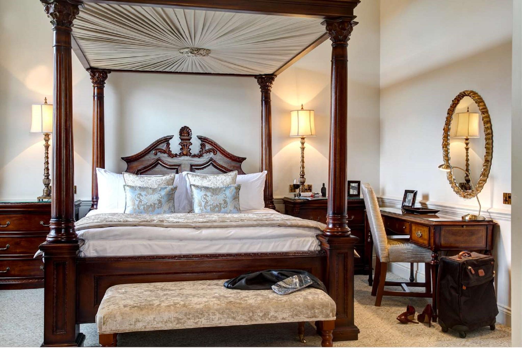 Macdonald Bath Spa Hotel Εξωτερικό φωτογραφία The photo showcases a beautifully designed bedroom featuring a four-poster canopy bed with intricate woodwork and elegant drapery. The bed is adorned with plush pillows and a decorative bedspread. On either side of the bed, there are stylish lamps il