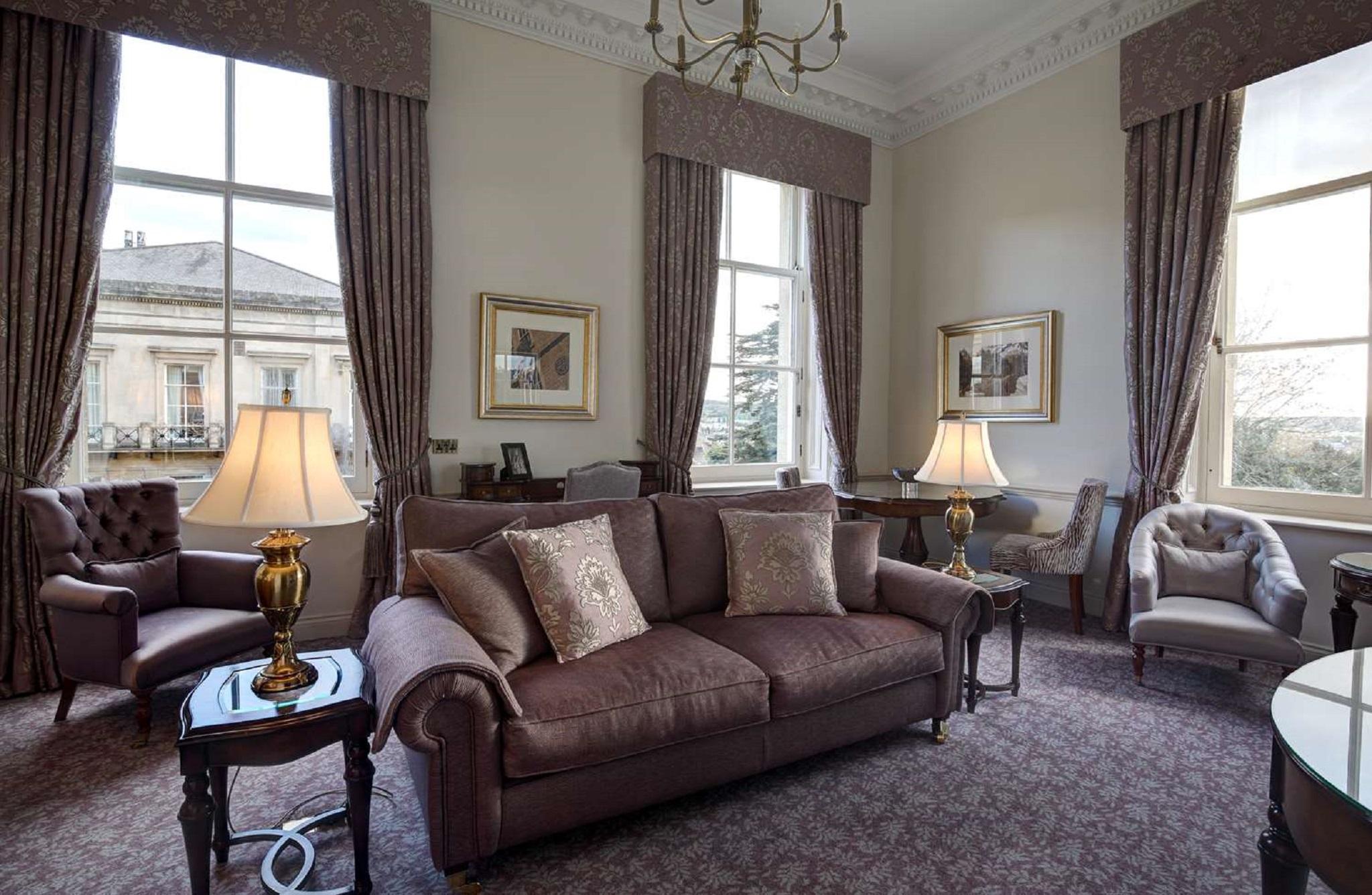 Macdonald Bath Spa Hotel Εξωτερικό φωτογραφία The photo shows a well-furnished living room with an elegant and cozy atmosphere. There is a brown couch with decorative pillows in the center. Two armchairs are positioned next to it, with a small table in the middle. The room features large windows