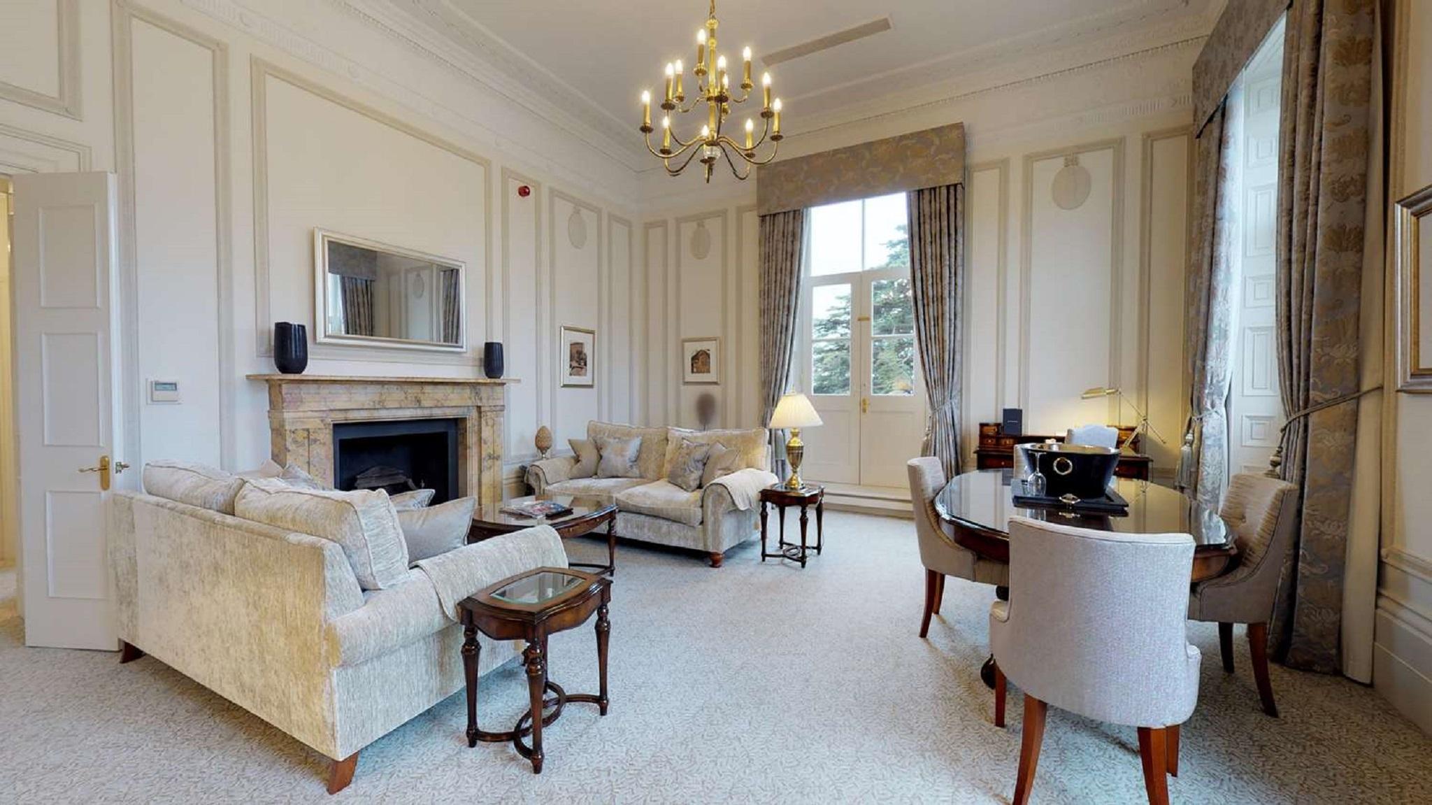 Macdonald Bath Spa Hotel Εξωτερικό φωτογραφία The photo shows an elegant living room with a classic design. It features a large chandelier hanging from the ceiling, providing soft lighting. The walls are adorned with decorative moldings and have a light color. 

In the center, there are two plus