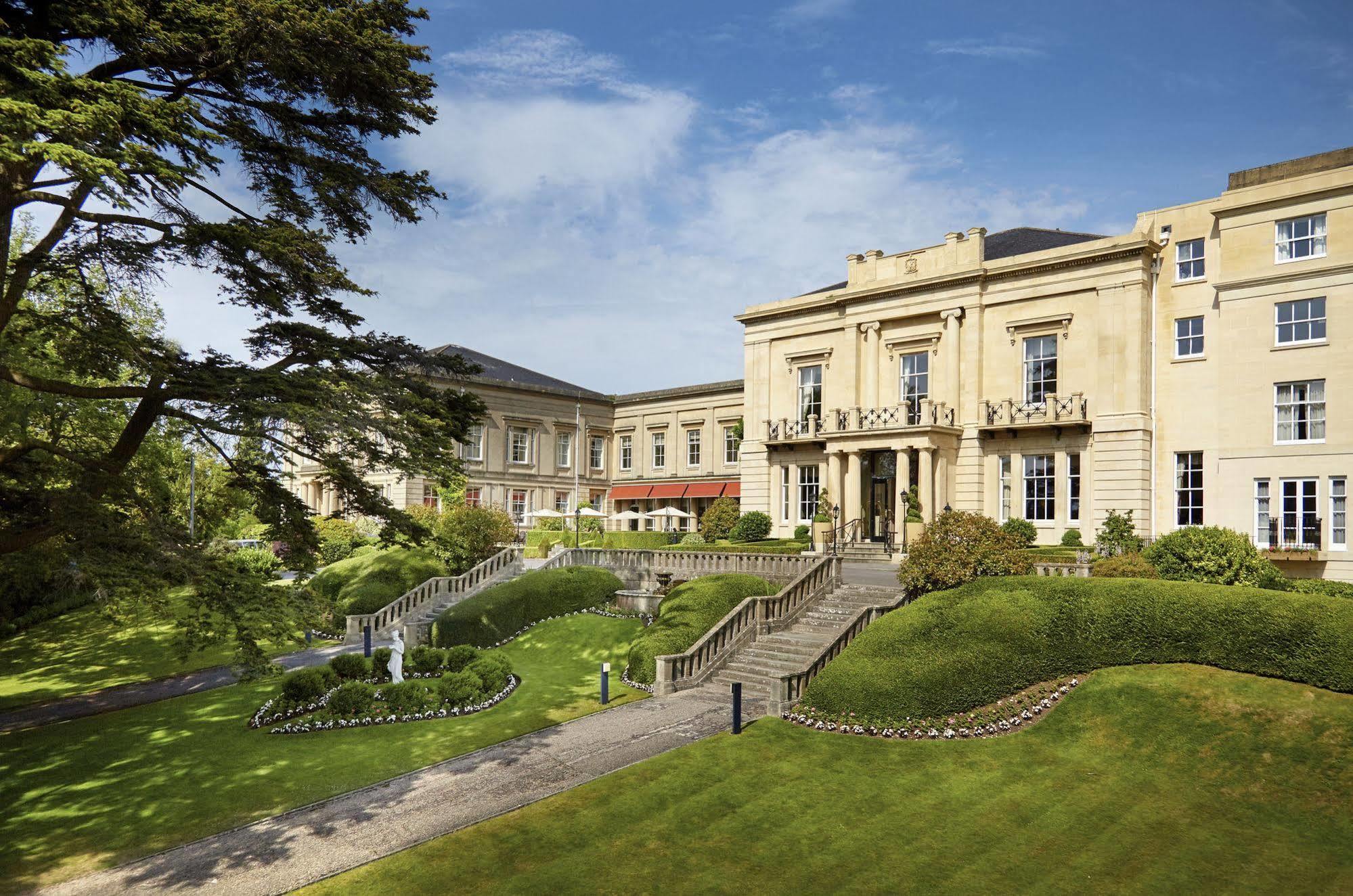 Macdonald Bath Spa Hotel Εξωτερικό φωτογραφία The photo shows a grand building, likely a hotel or estate, surrounded by well-manicured gardens and lawns. The architecture appears elegant, with multiple stories and large windows. There are steps leading up to the entrance, and the setting include