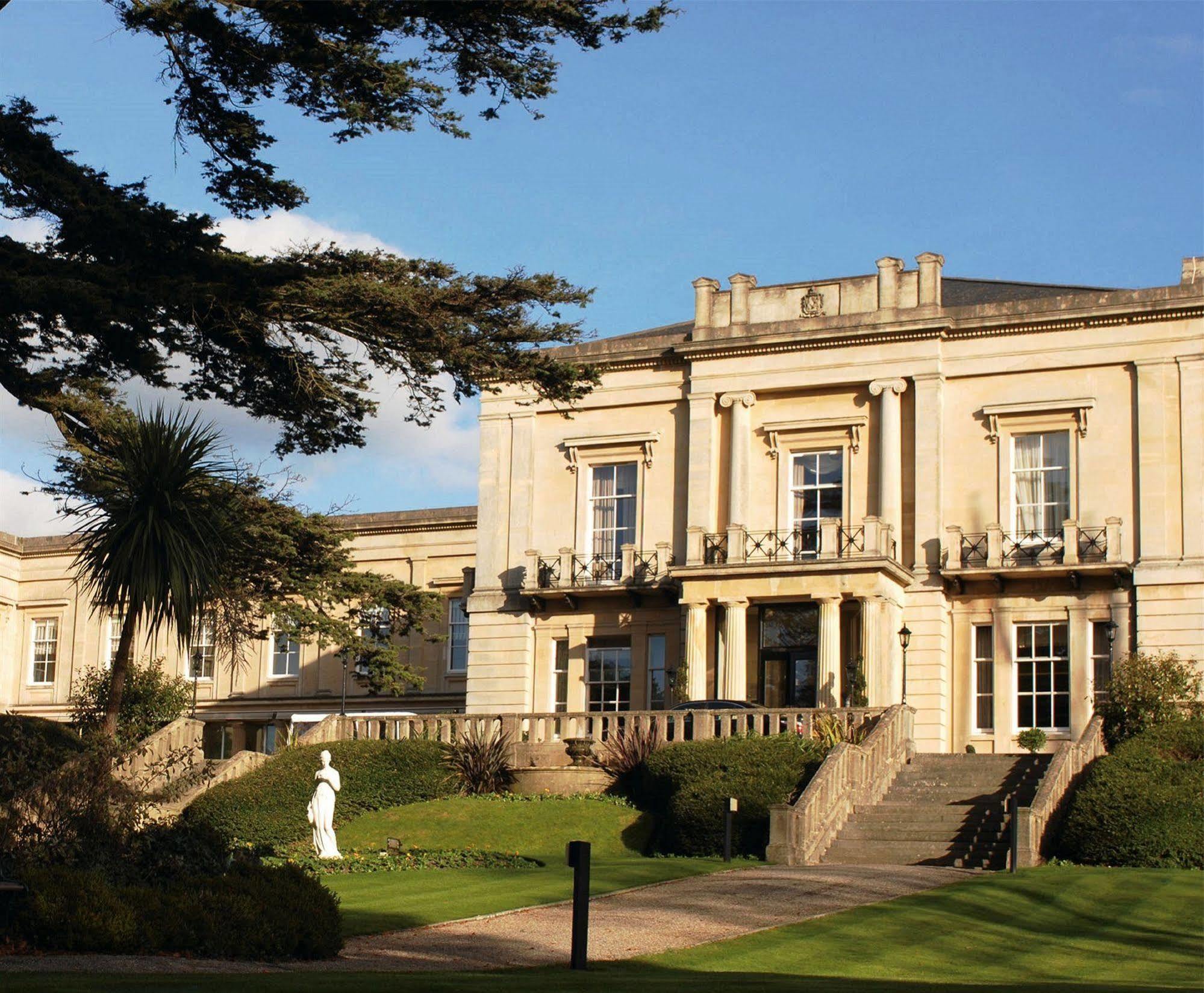 Macdonald Bath Spa Hotel Εξωτερικό φωτογραφία The photo shows an elegant building with classical architecture, featuring large windows and decorative elements. The facade is light-colored, and there are several balconies. In front of the building, there is a landscaped area with greenery, includ